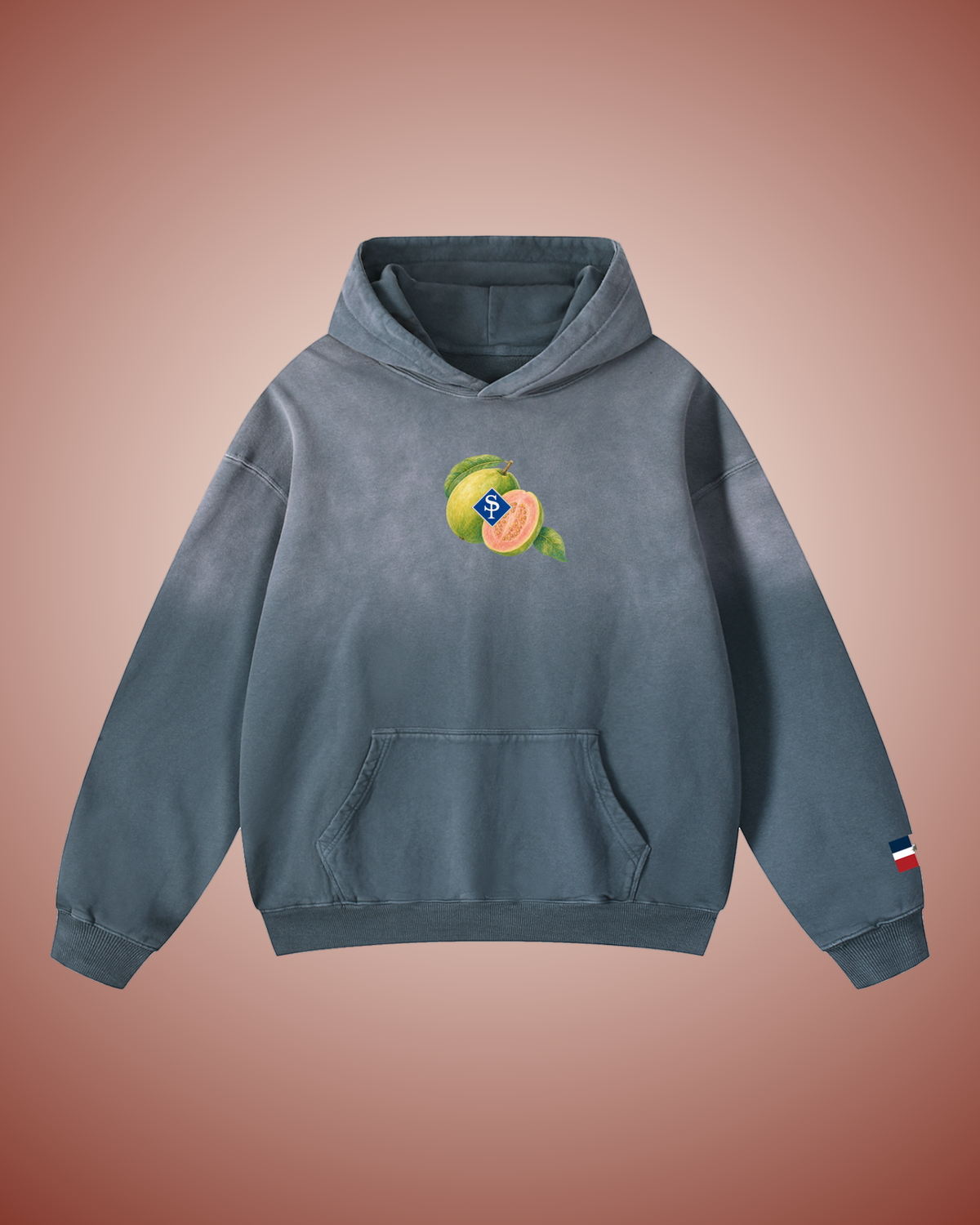 Front of the slate blue hoodie, washed pale at the shoulders: a whole guava and a halved one showing pink flesh, the blue SP diamond laid over them, small at the chest.