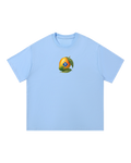 Light blue boxy tee with a small chest illustration of a whole mango, leaves, and a blue SP diamond on its cheek.